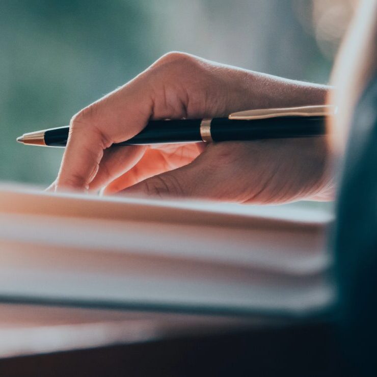 hand with pen writing on a notebook