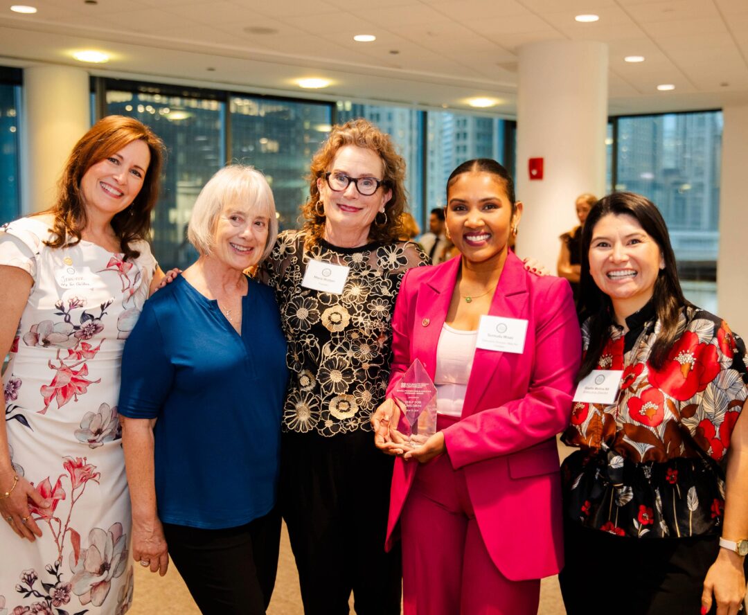 Group of women smiling together at an indoor event.
